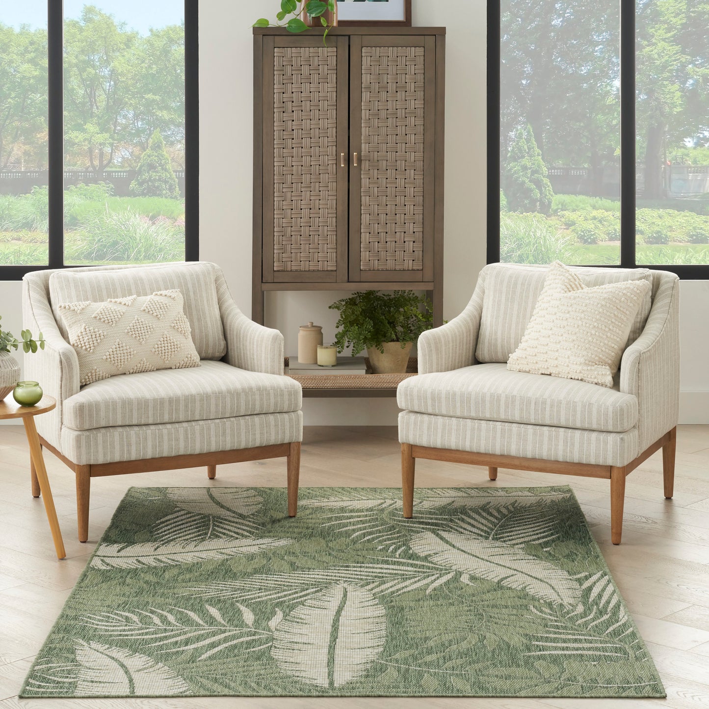 Outdoor rug 5' x 7' on a patio with two beige striped chairs, wooden legs, and a wicker cabinet.