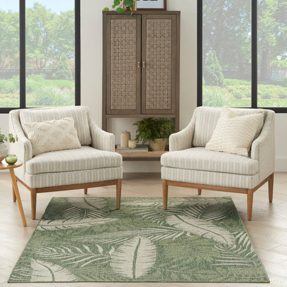 Outdoor rug 5' x 7' on a patio with two beige striped chairs, wooden legs, and a wicker cabinet.