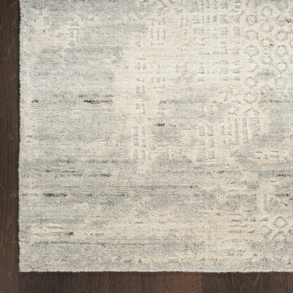 Distressed gray and ivory abstract patterned area rug on dark wood floor.