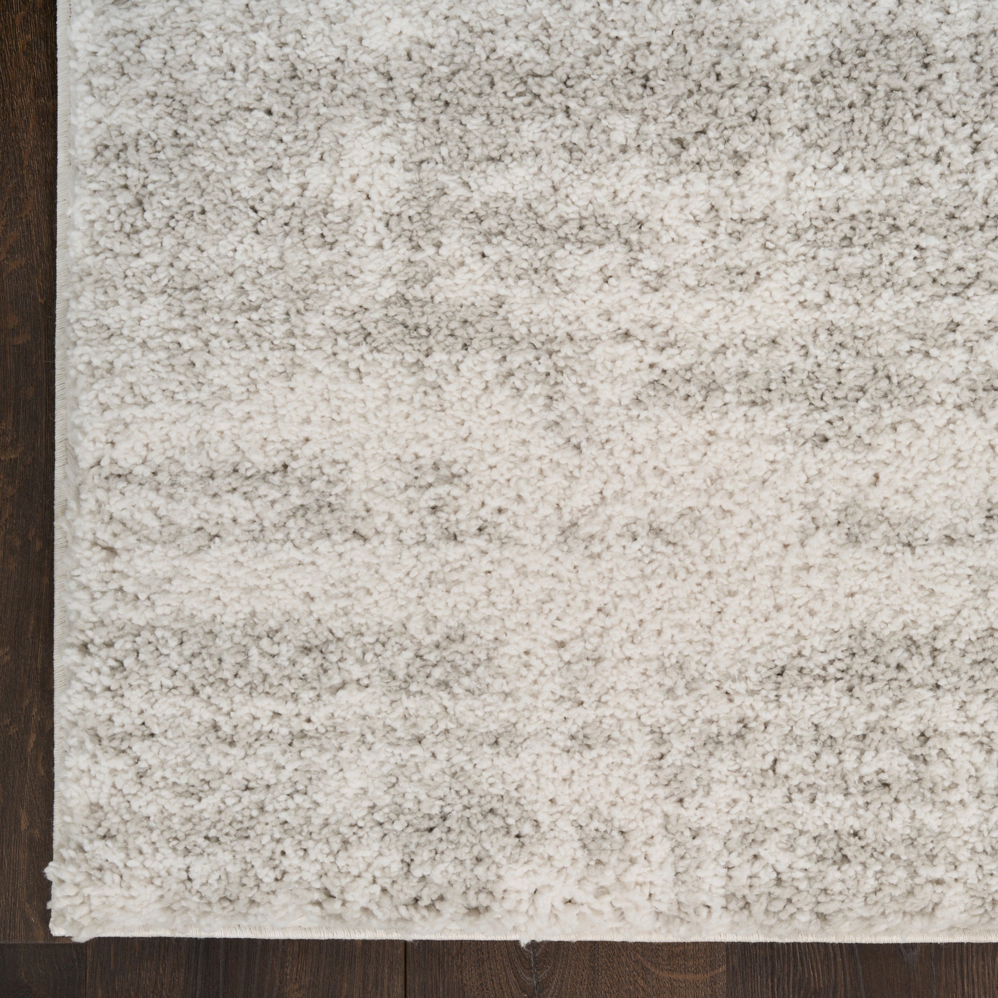 Cream beige shag area rug with dense plush pile on dark wood floor.