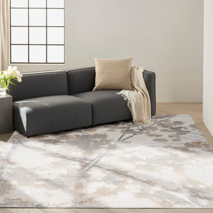 Dark gray fabric sectional with beige cushion and throw on a neutral abstract-pattern rug in a modern living room.