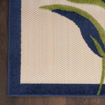 Beige textured area rug with navy border and blue-green curved motif on dark wood floor.