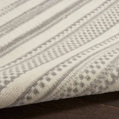 Cream and gray striped woven rug with geometric patterns, soft textured fabric folded on dark wood floor.
