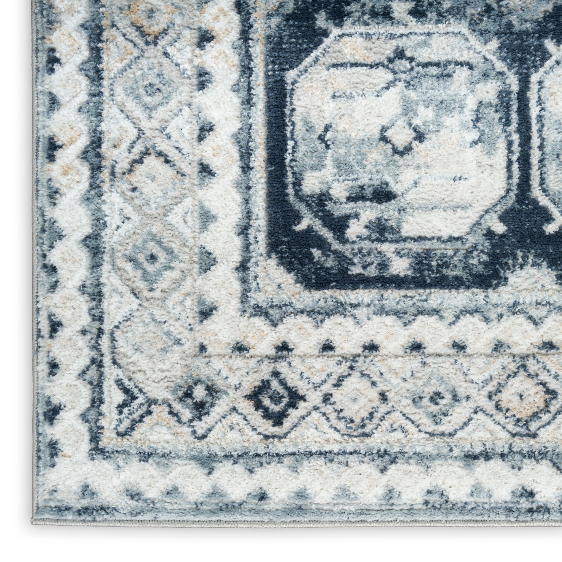Close-up of blue, ivory, and gray geometric patterned area rug with border and medallion motif.