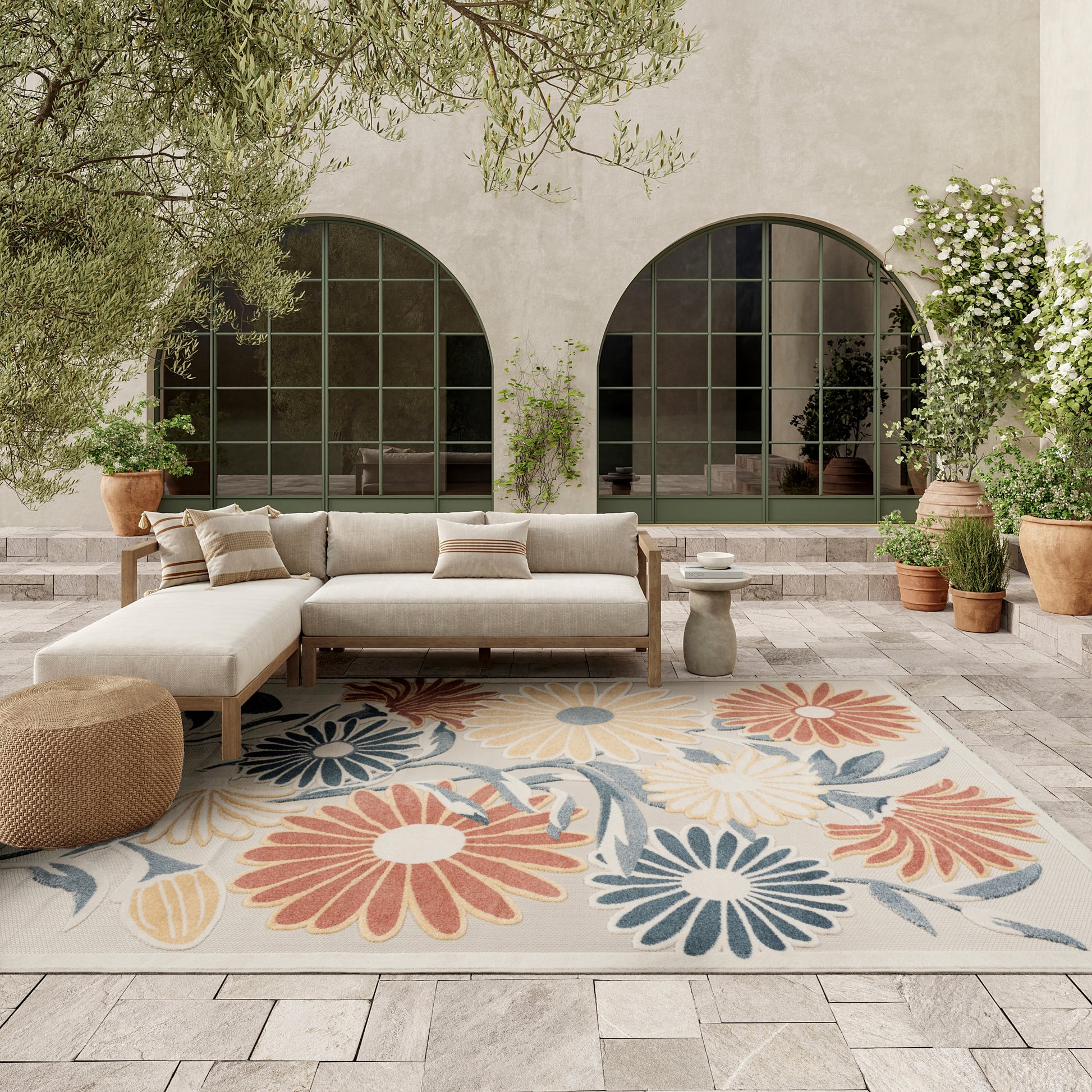 Beige outdoor rug, 8' x 11', in a setting with arched green-framed windows and potted plants.