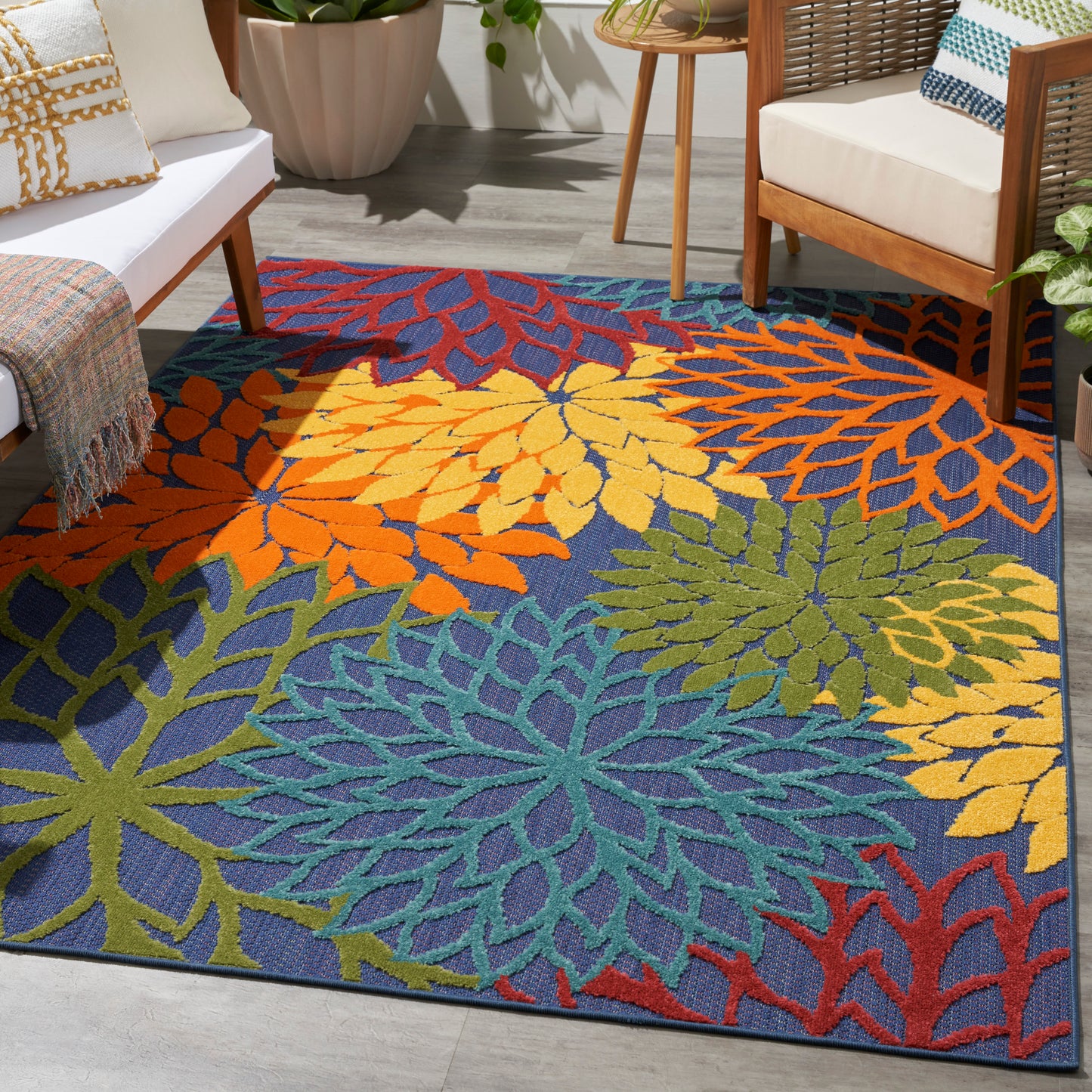 Vibrant multicolored leaf-pattern area rug in blue with orange, yellow, green and teal motifs in a modern living room.