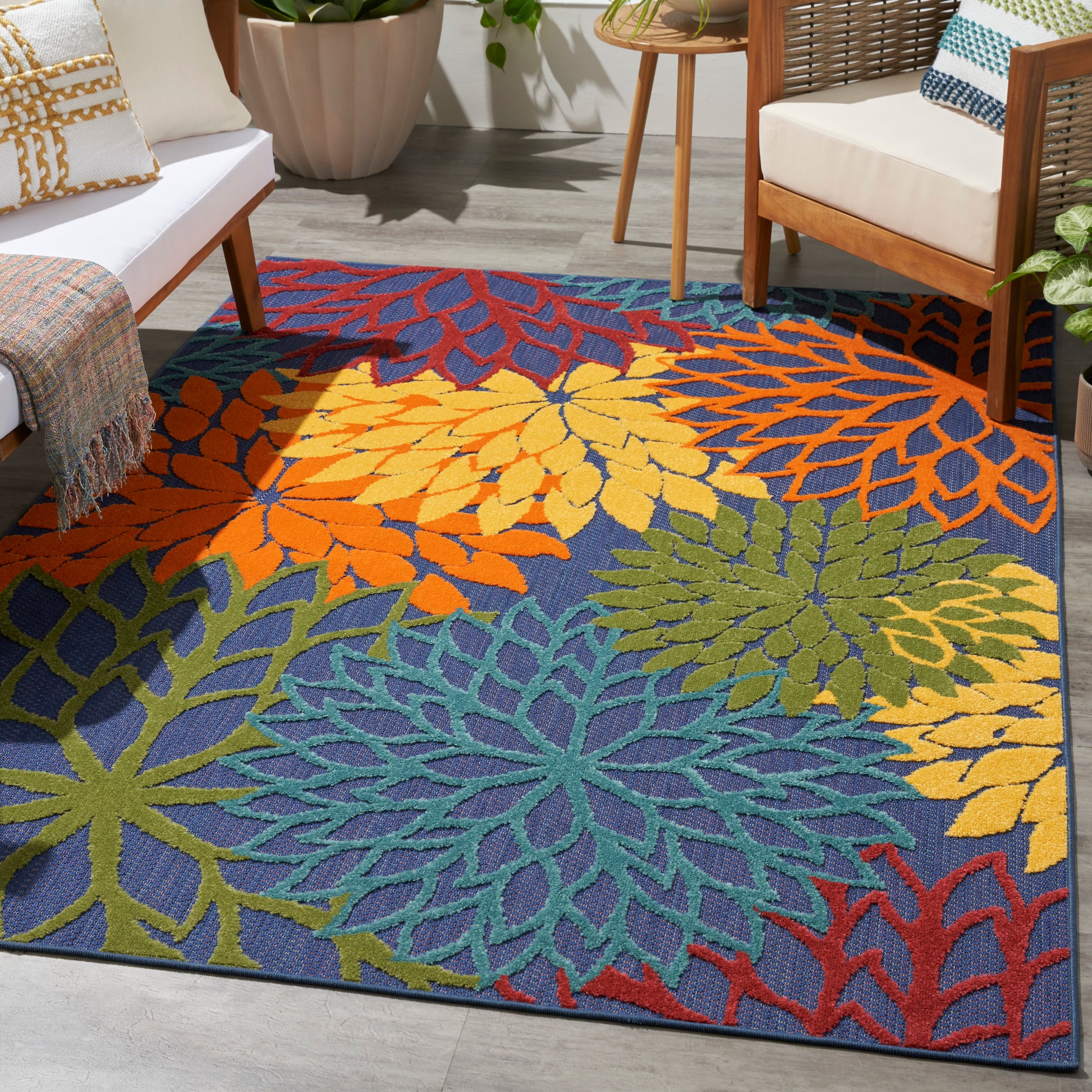 Vibrant multicolored leaf-pattern area rug in blue with orange, yellow, green and teal motifs in a modern living room.