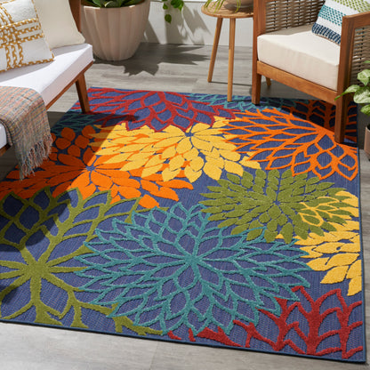 Vibrant multicolored leaf-pattern area rug in blue with orange, yellow, green and teal motifs in a modern living room.