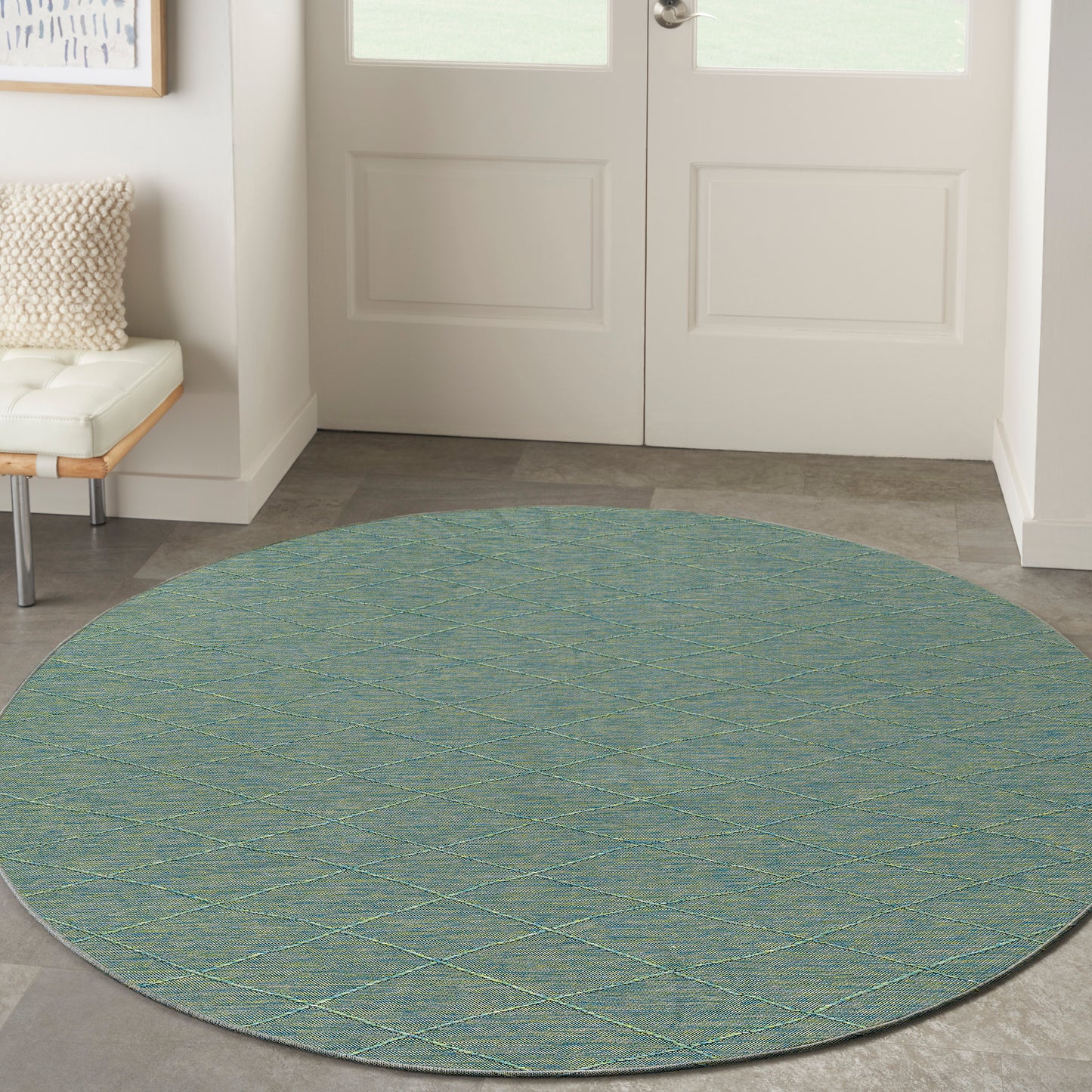 Round teal flat-weave rug with pale yellow lattice diamonds for entryway.