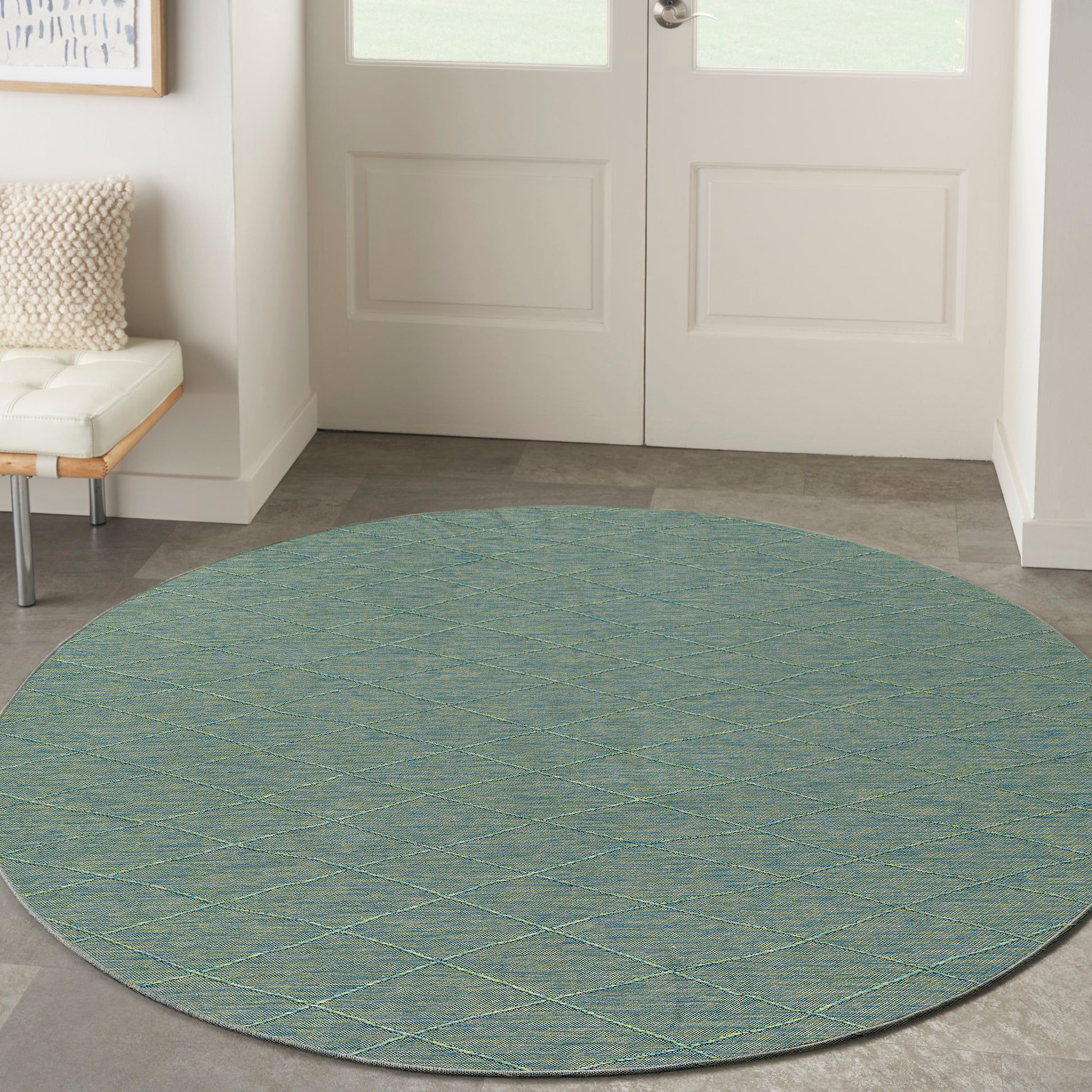 Round teal flat-weave rug with pale yellow lattice diamonds for entryway.