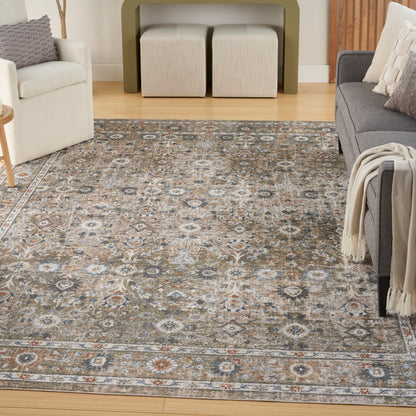 Living room with a large ornate patterned rug in gray, beige and blue; gray sofa, beige armchair, wooden floor.