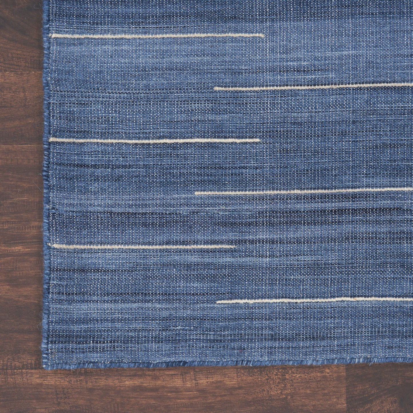 Blue denim-textured rug with thin white horizontal stitched lines; modern minimalist rug, 8' x 10'.