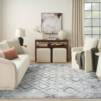 Neutral living room: cream sofa, blush pillow, wooden console, beige ottomans, blue rug, armchair by window.