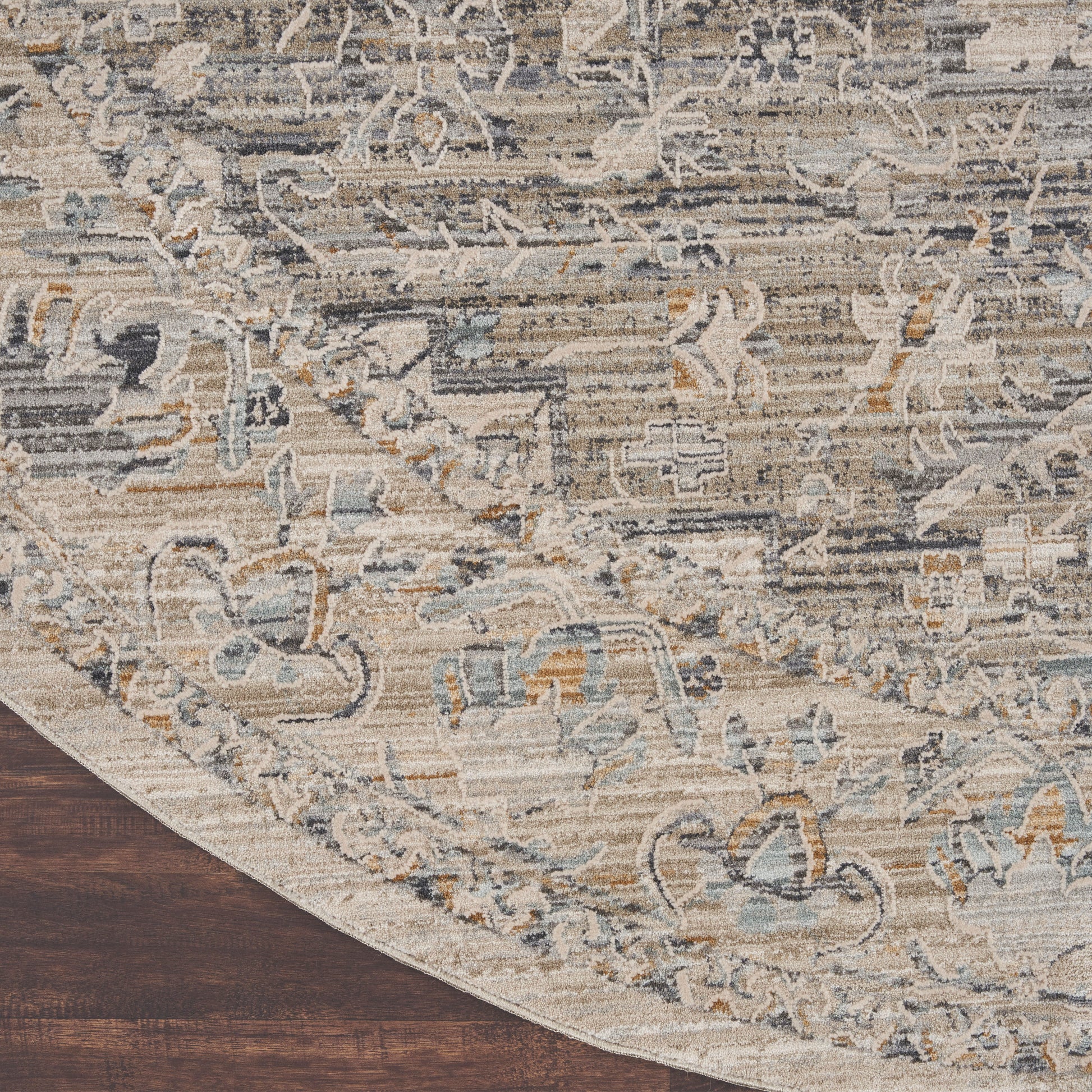 8' round oriental-style rug in beige, ivory, and blue with a distressed floral pattern on a dark wood floor.
