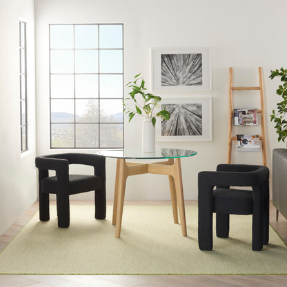 Minimalist dining set: round glass table on light wood base, two black curved stools, plant centerpiece, grid-windowed room.
