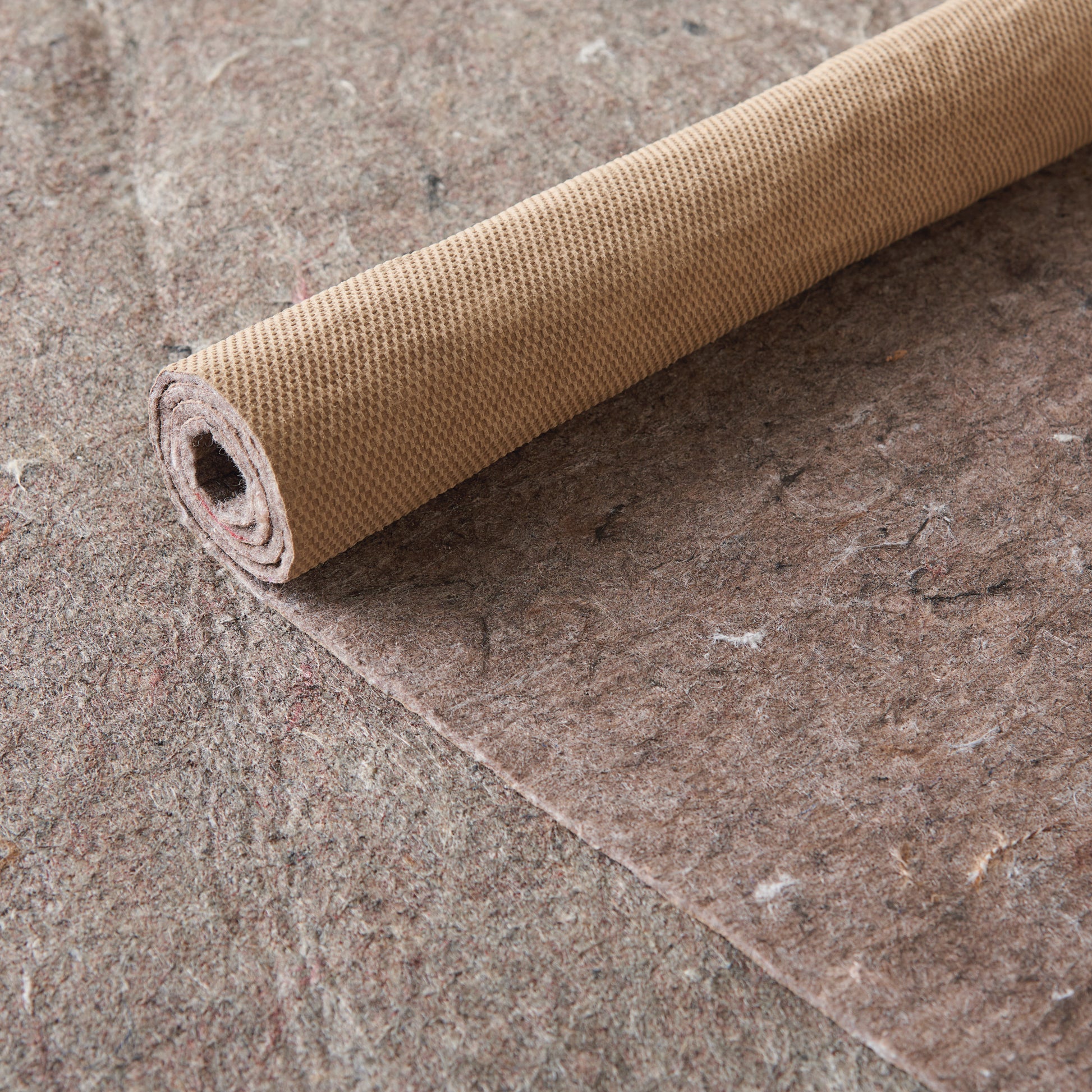 Rolled tan woven rug with a small waffle texture.