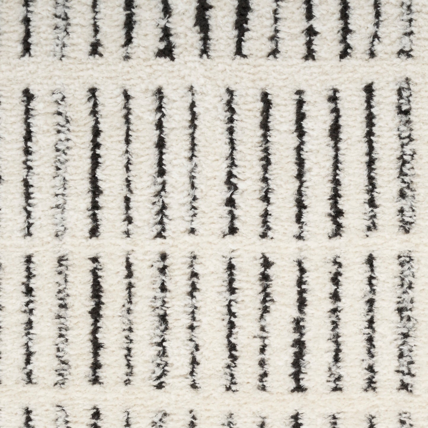 Cream shag rug with bold black vertical stripes; plush tufted texture, modern geometric decor.