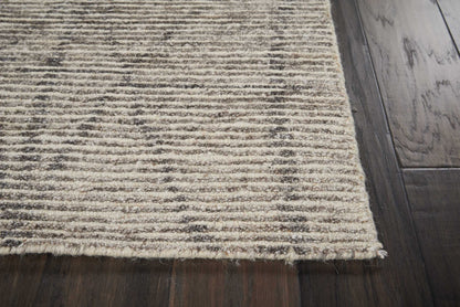 Beige textured area rug with brown horizontal stripes and fringed edge on dark wooden floor.