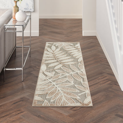 Neutral hallway runner rug with beige botanical leaf pattern on light grey background, laid over dark herringbone wood floor.
