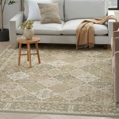 Light gray sofa, beige floral-patterned rug, round wooden side table & vase, beige throw & mustard pillow.