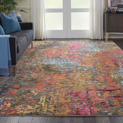 Abstract multicolor area rug in a living room with a dark gray sofa, blue cushions, and light curtains.