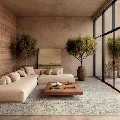 Beige sectional sofa, low wood coffee table, geometric rug, potted trees, floor-to-ceiling glass walls, modern living room.