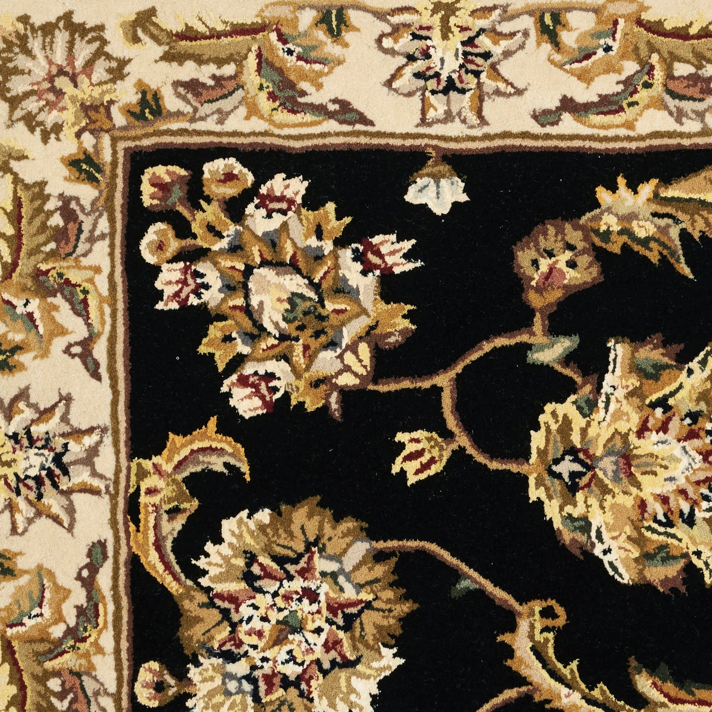Oriental rug with a black central field and cream border, featuring gold, ivory, and burgundy floral motifs.