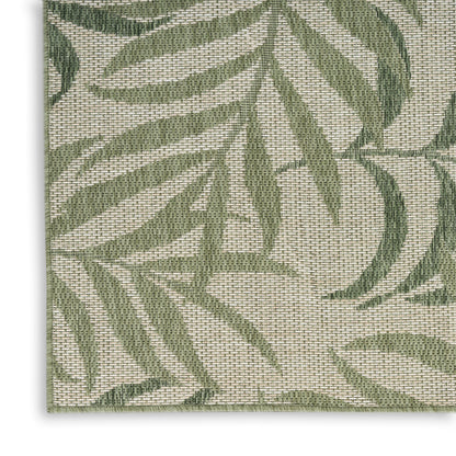 Beige woven textile with green palm leaf pattern; natural fiber rug or placemat for tropical decor.