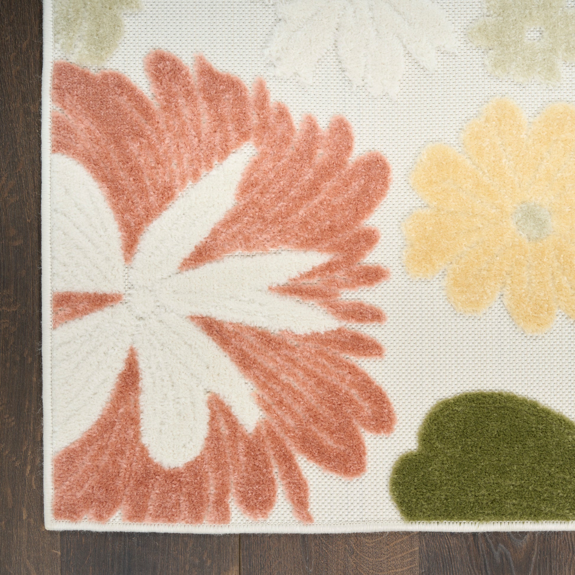 Tufted floral area rug with bold red-orange petals, white center, yellow blooms and green foliage on cream background.