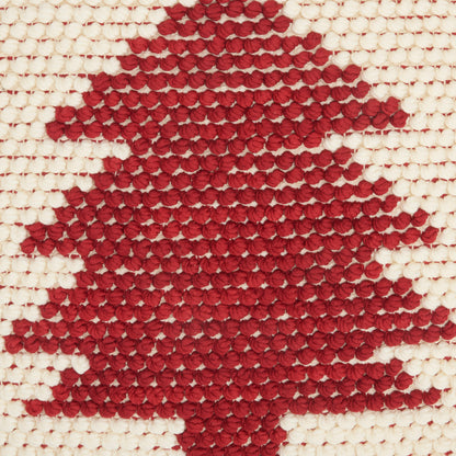 Red knitted maple-leaf motif on cream woven fabric, decorative textile.