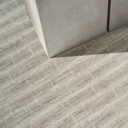 Gray concrete block corner resting on beige woven rug with a subtle rectangular grid pattern.