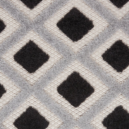 Geometric tufted rug with repeating black diamonds inside light gray/cream diamond outlines; modern monochrome pattern.