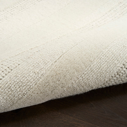 Cream textured rug with raised stripe pattern on dark wood floor.