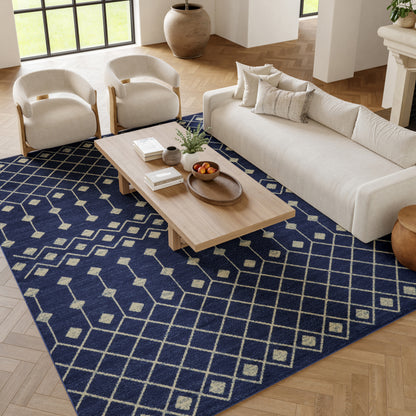 Neutral living room featuring a navy geometric area rug, light wood coffee table, beige sofa, & two cream armchairs.