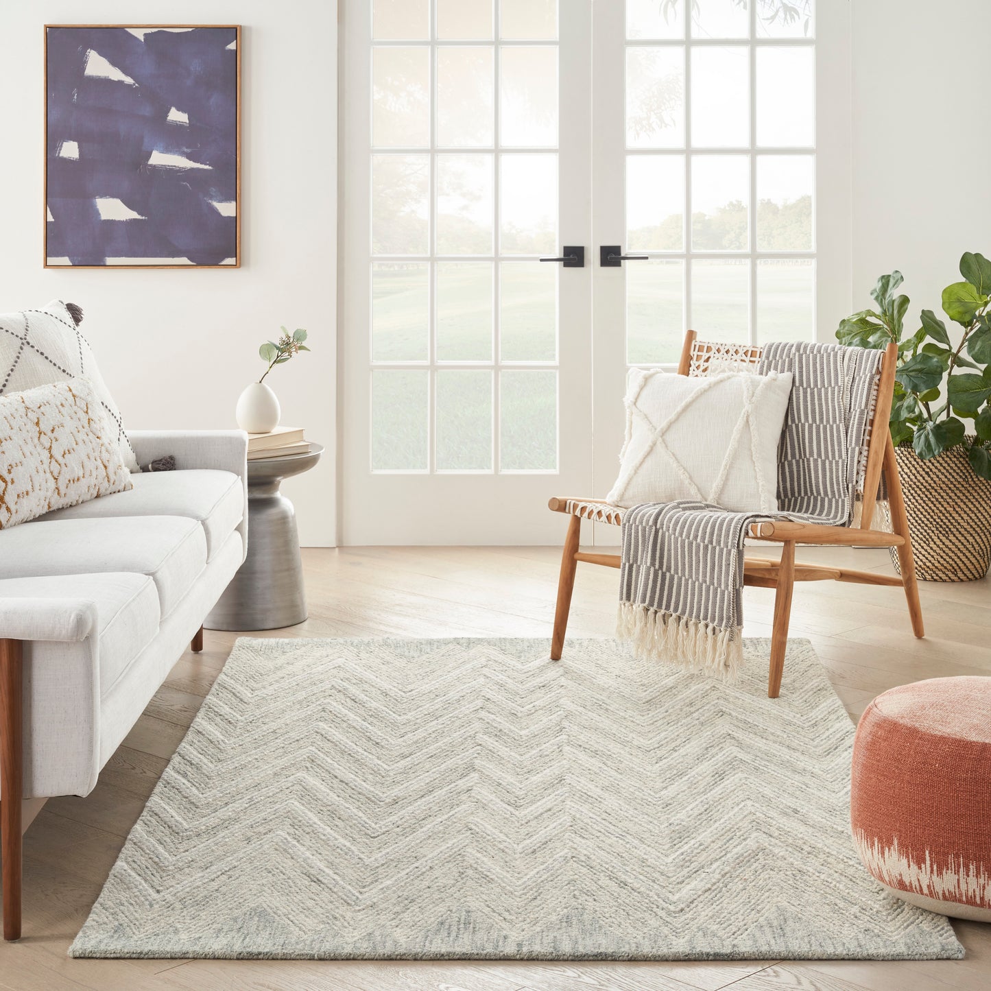 Light-gray chevron area rug with plush texture in a neutral modern living room, beige sofa and wooden chair