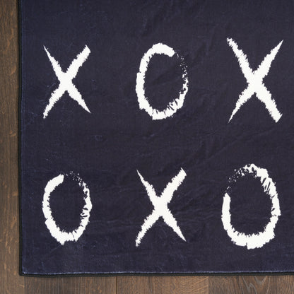 Navy tic-tac-toe rug with white chalky Xs and Os on dark fabric, placed on a wooden floor.