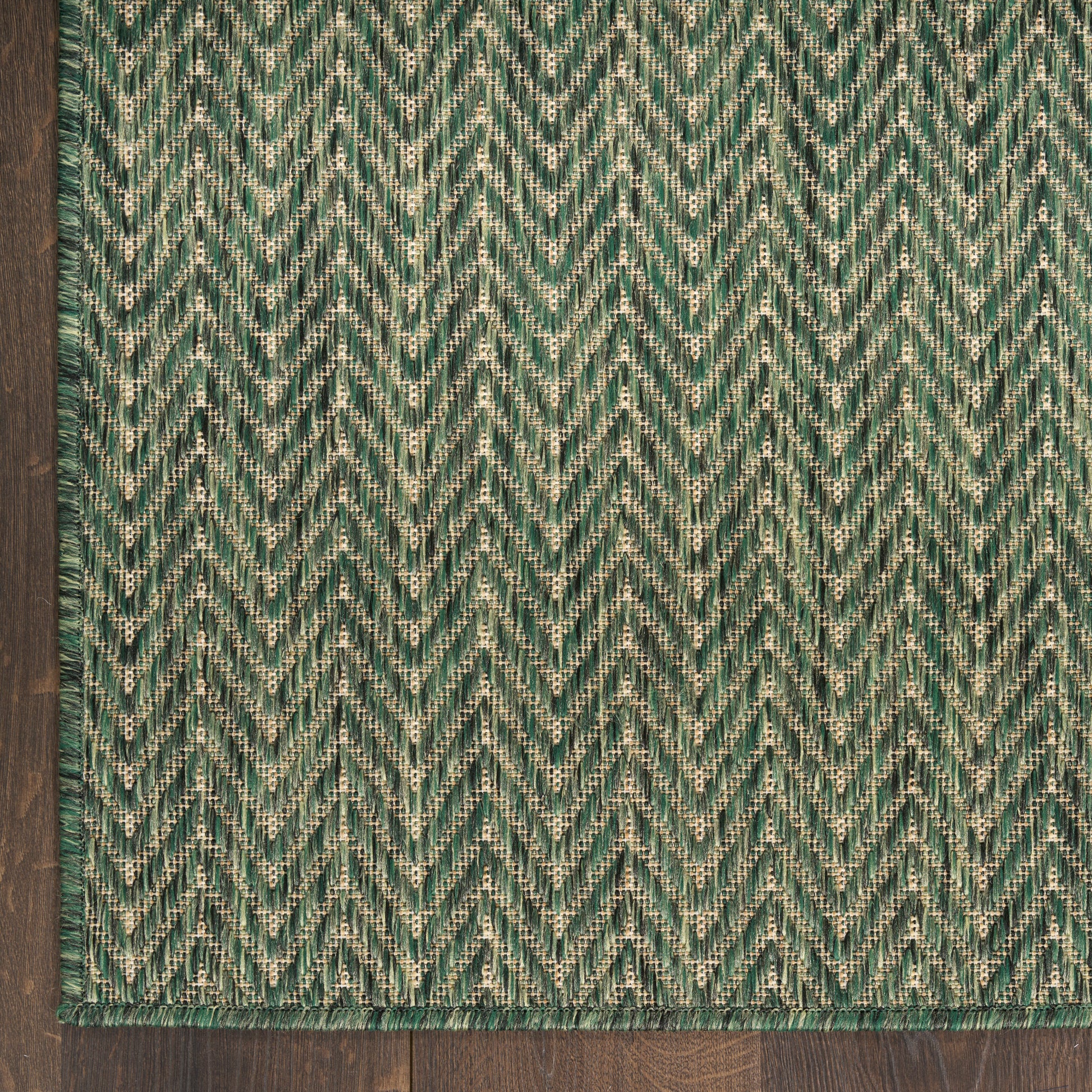Teal-green chevron woven rug with emerald and cream flecks and bordered edges.
