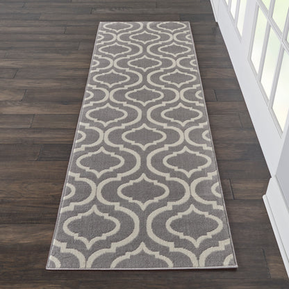 Grey & beige trellis-patterned 7' long runner rug on dark wood flooring beside a glass-paneled wall.