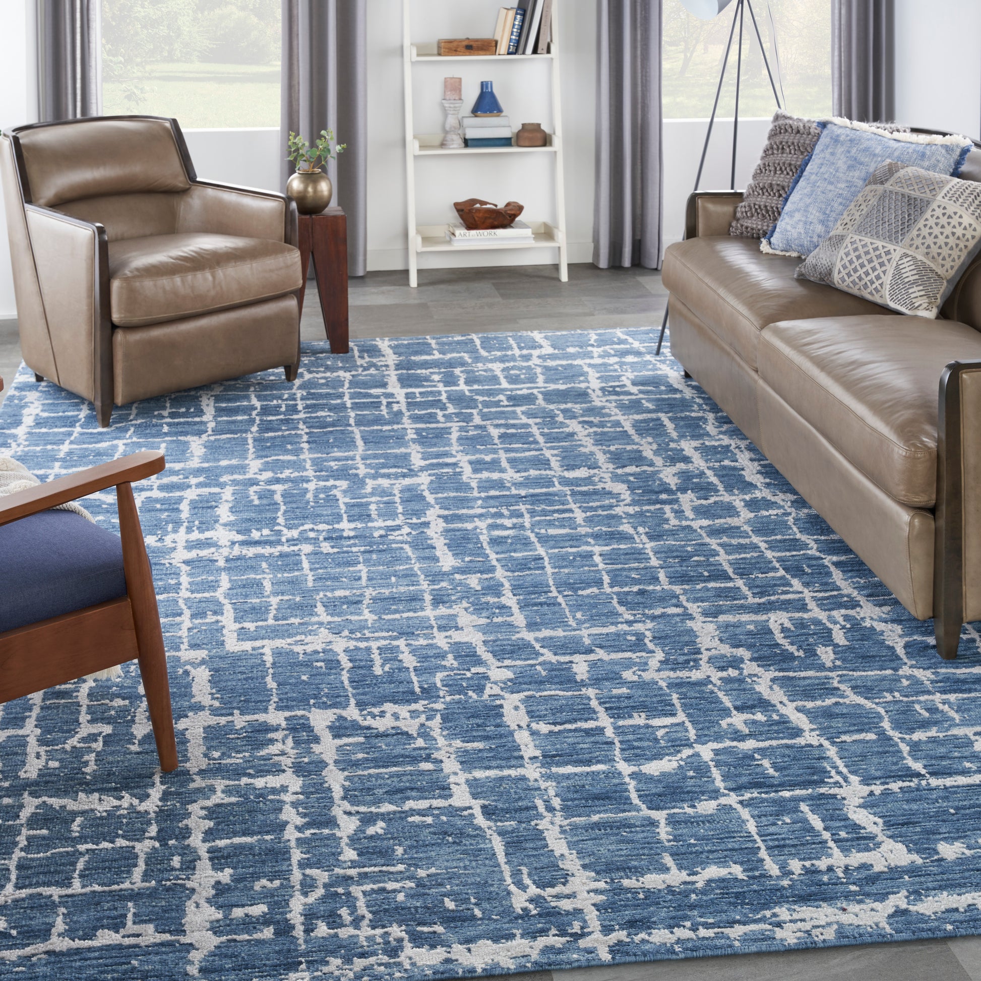 Brown leather sofa and armchairs around a blue-and-white geometric rug in a modern living room.