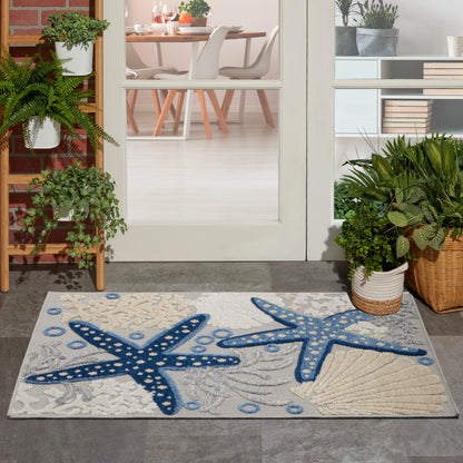 Outdoor doormat featuring blue starfish on a sandy background at a glass door entry.