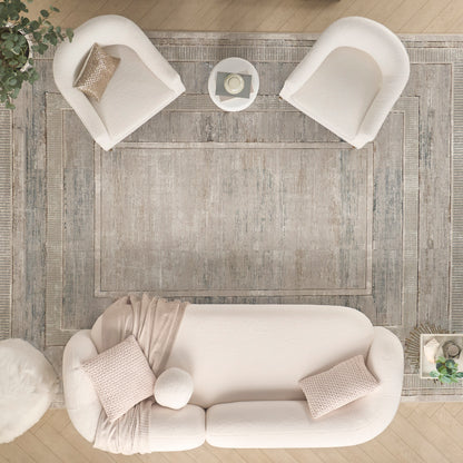Top-down view of a living room with a gray rug under a curved beige sofa, two white armchairs, and a coffee table.