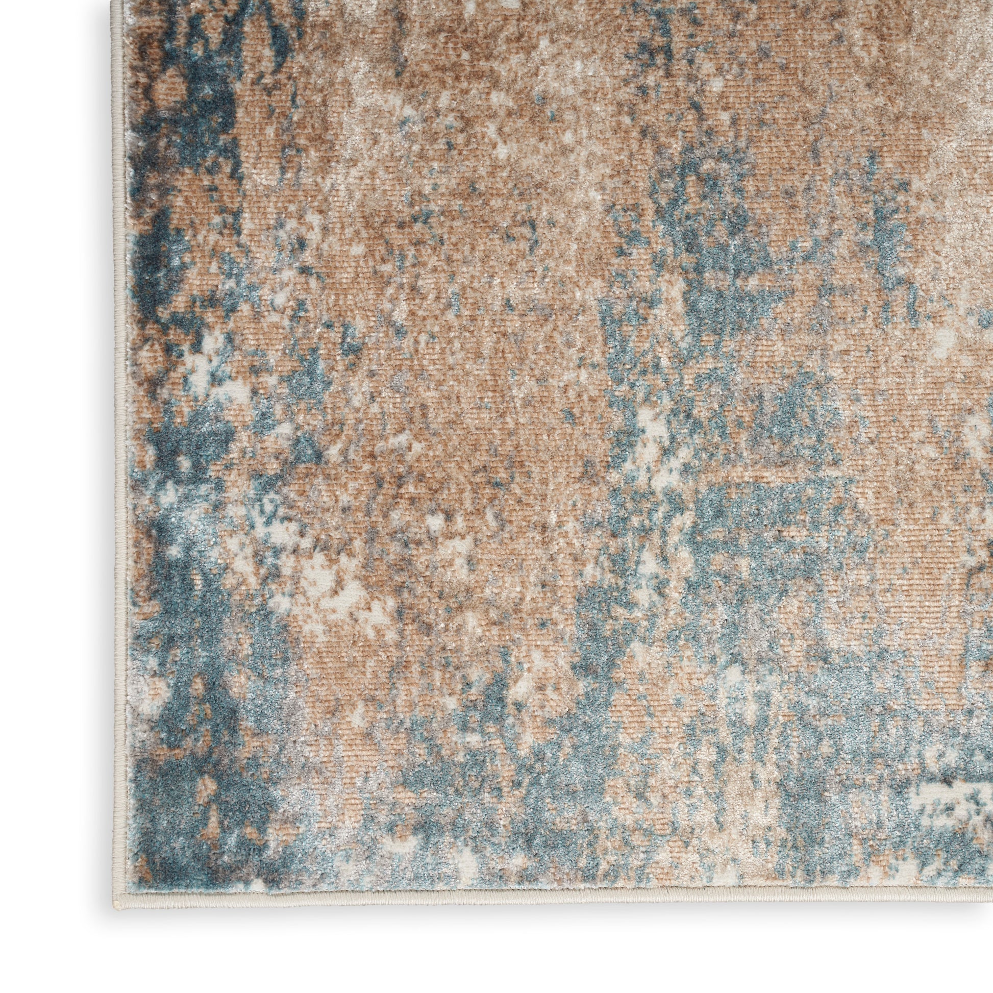Abstract distressed area rug in tan, blue and ivory tones with a textured woven surface.