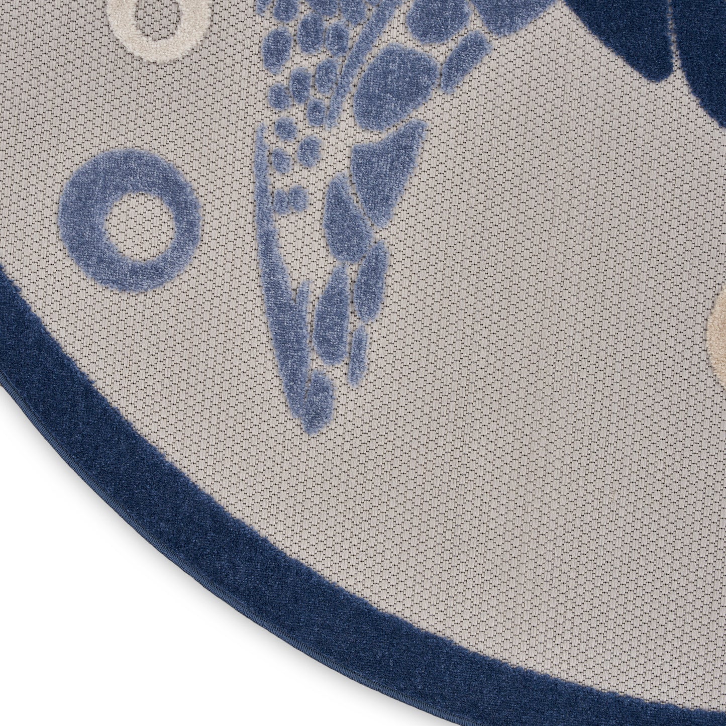 Round beige rug with blue abstract leaf pattern and dark blue border, textured woven surface.