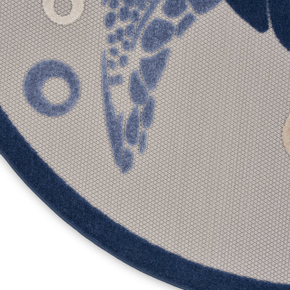 Round beige rug with blue abstract leaf pattern and dark blue border, textured woven surface.
