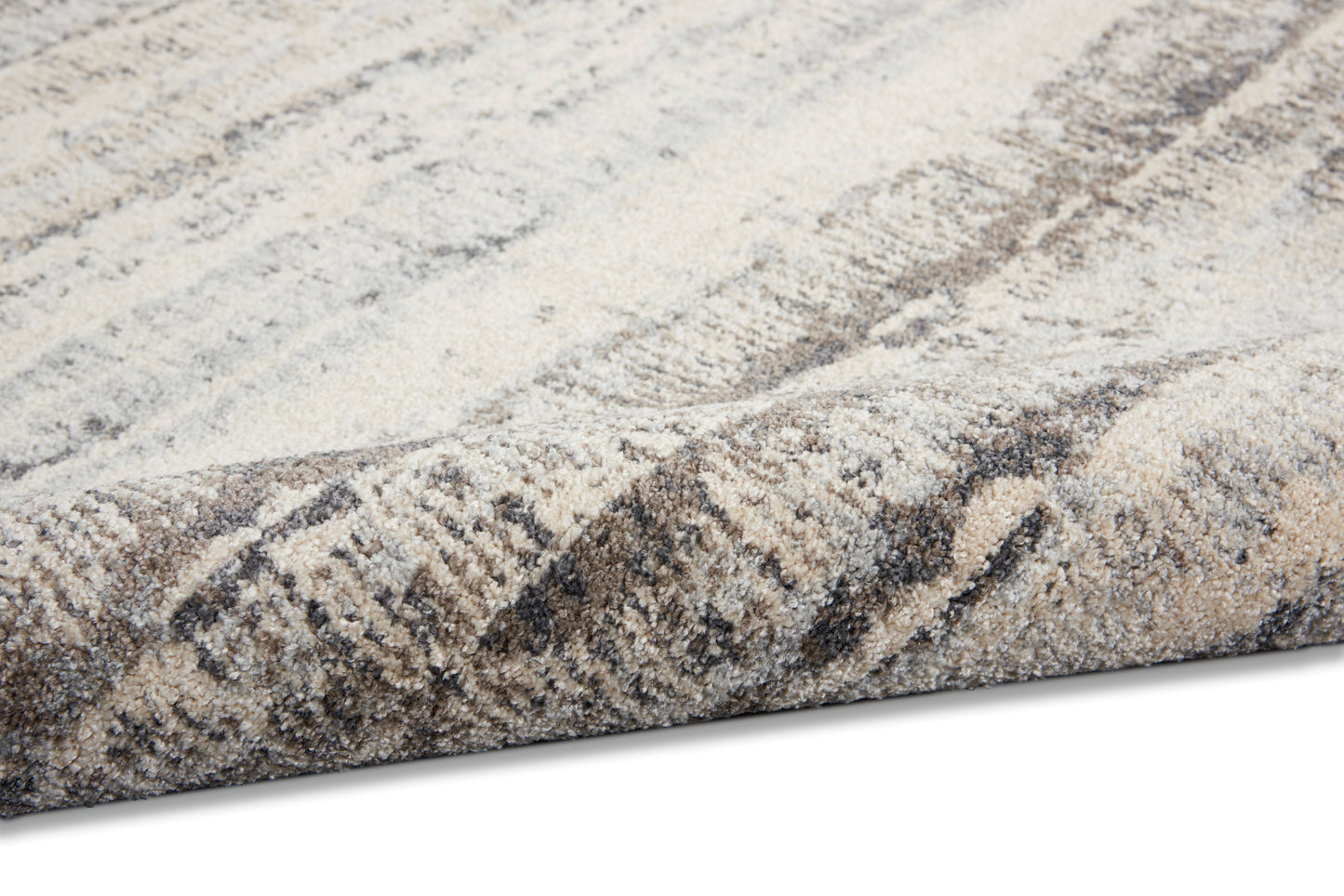 Soft beige and taupe woven rug with gray abstract pattern and thick plush pile, folded edge.