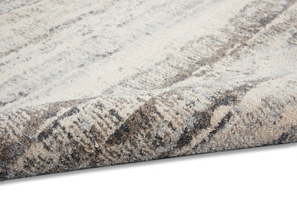 Soft beige and taupe woven rug with gray abstract pattern and thick plush pile, folded edge.