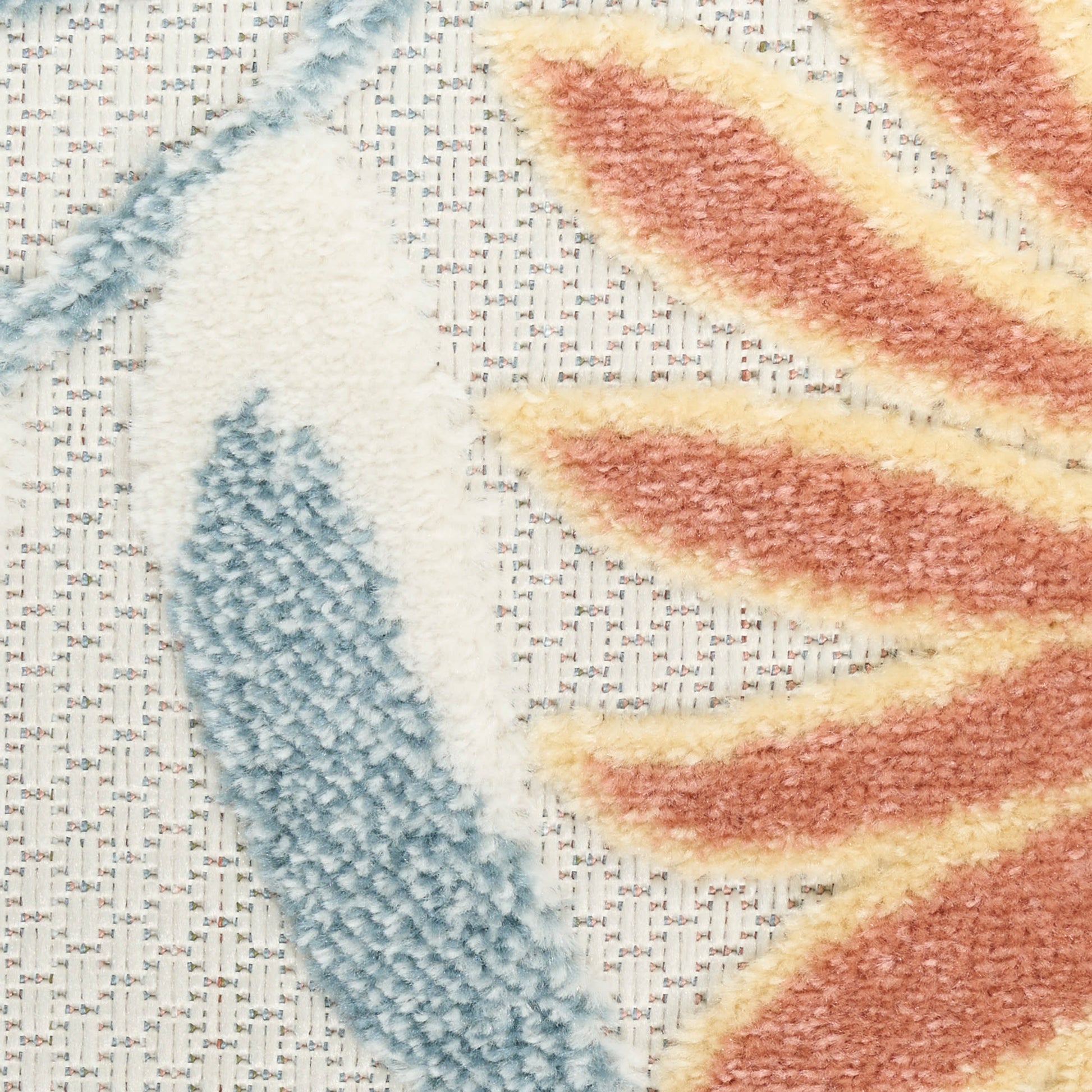 Close-up of a tufted rug featuring a blue leaf motif and orange-yellow leaf motif on a woven beige backing.