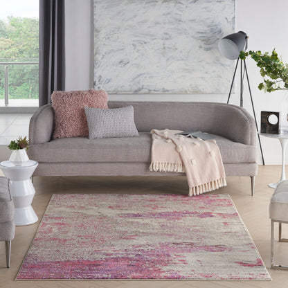 Contemporary living room with a light-gray curved sofa, pink shag pillow, gray cushion, blush throw; pink-toned abstract rug