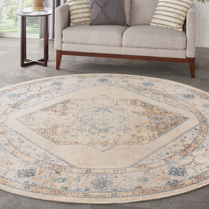 Round beige area rug with blue-gray floral border and central medallion under a beige sofa.