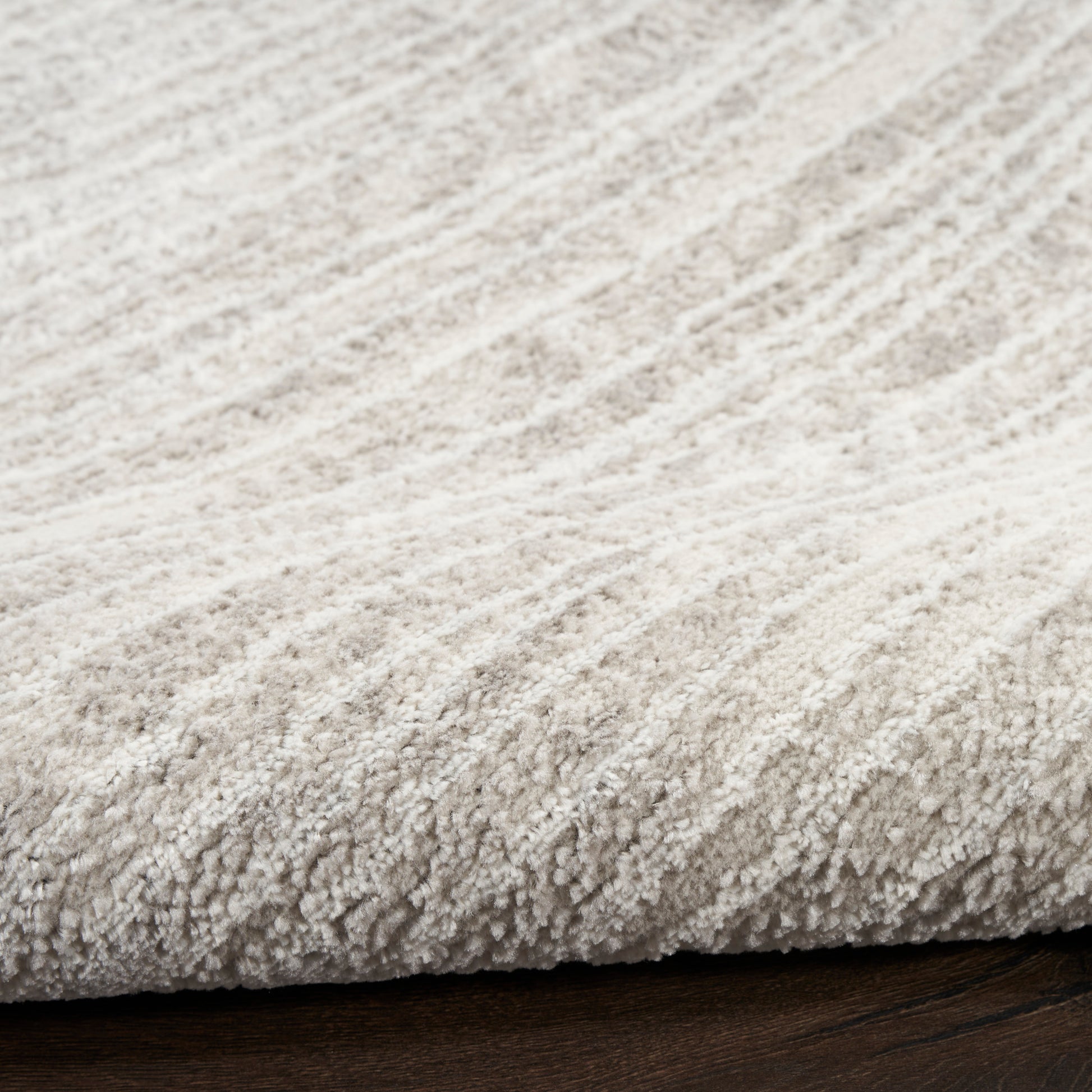 Cream shag rug with dense plush pile on dark wood floor, cozy living room decor.
